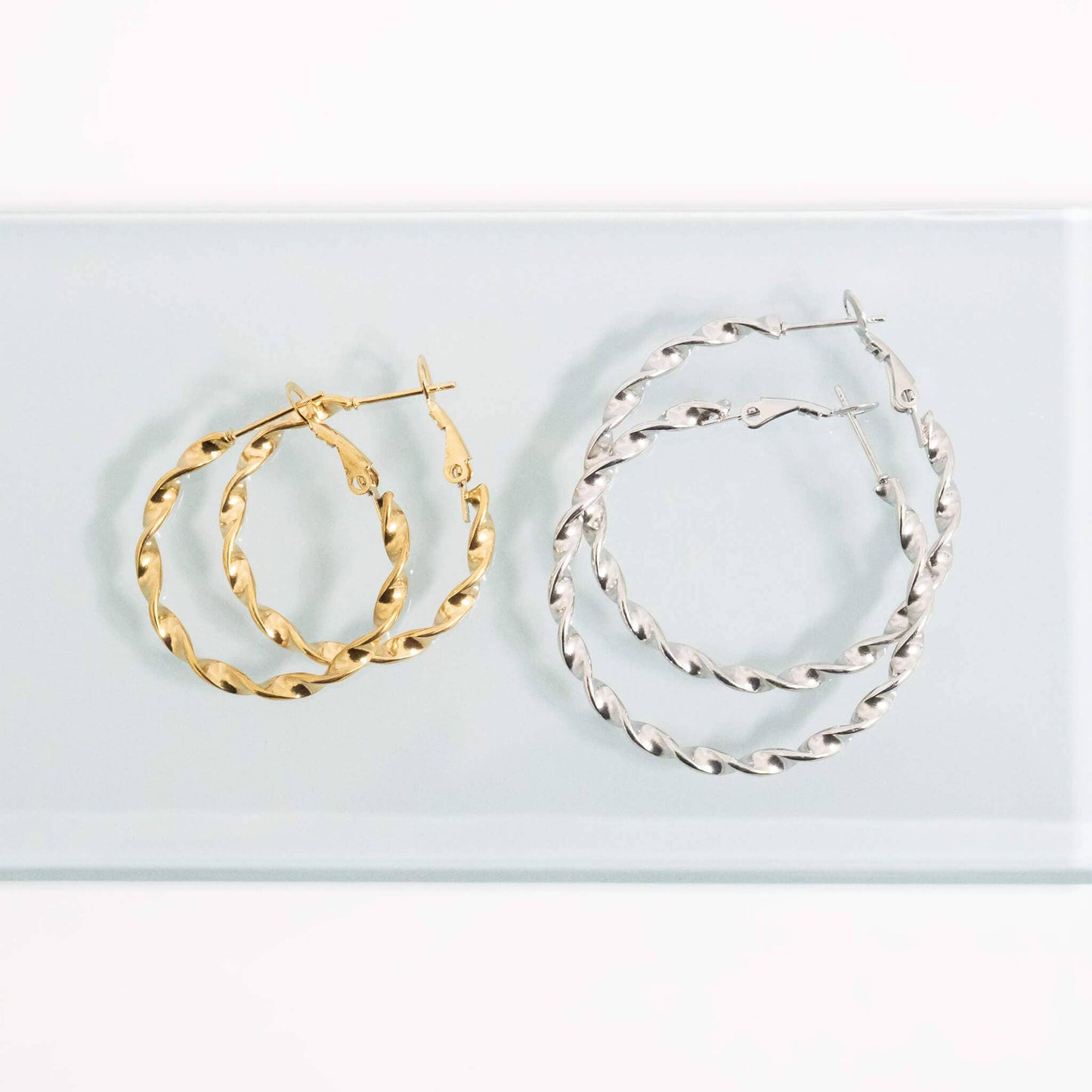 Gold and silver hoop earrings on a light blue background