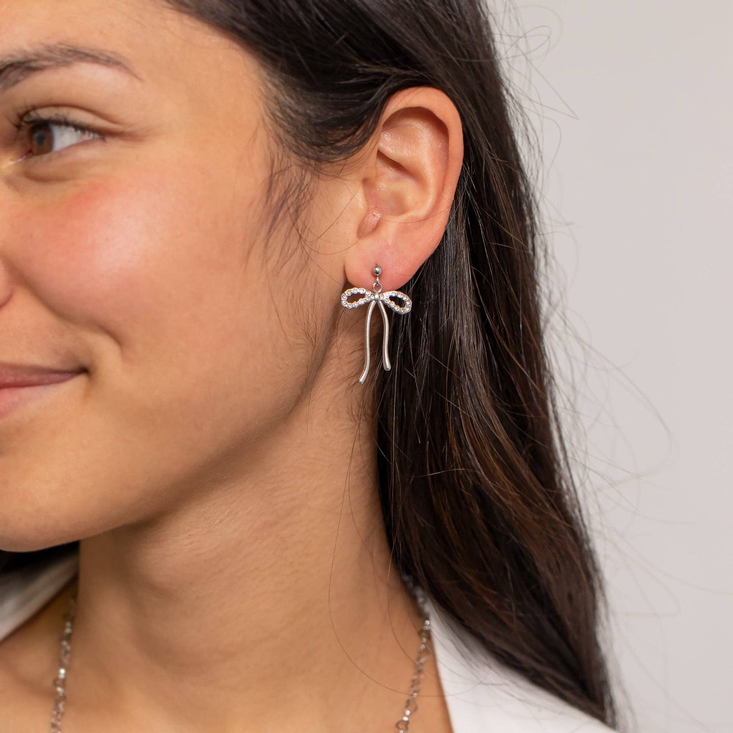 Close-up of a woman wearing a bow-shaped earring with a plain background