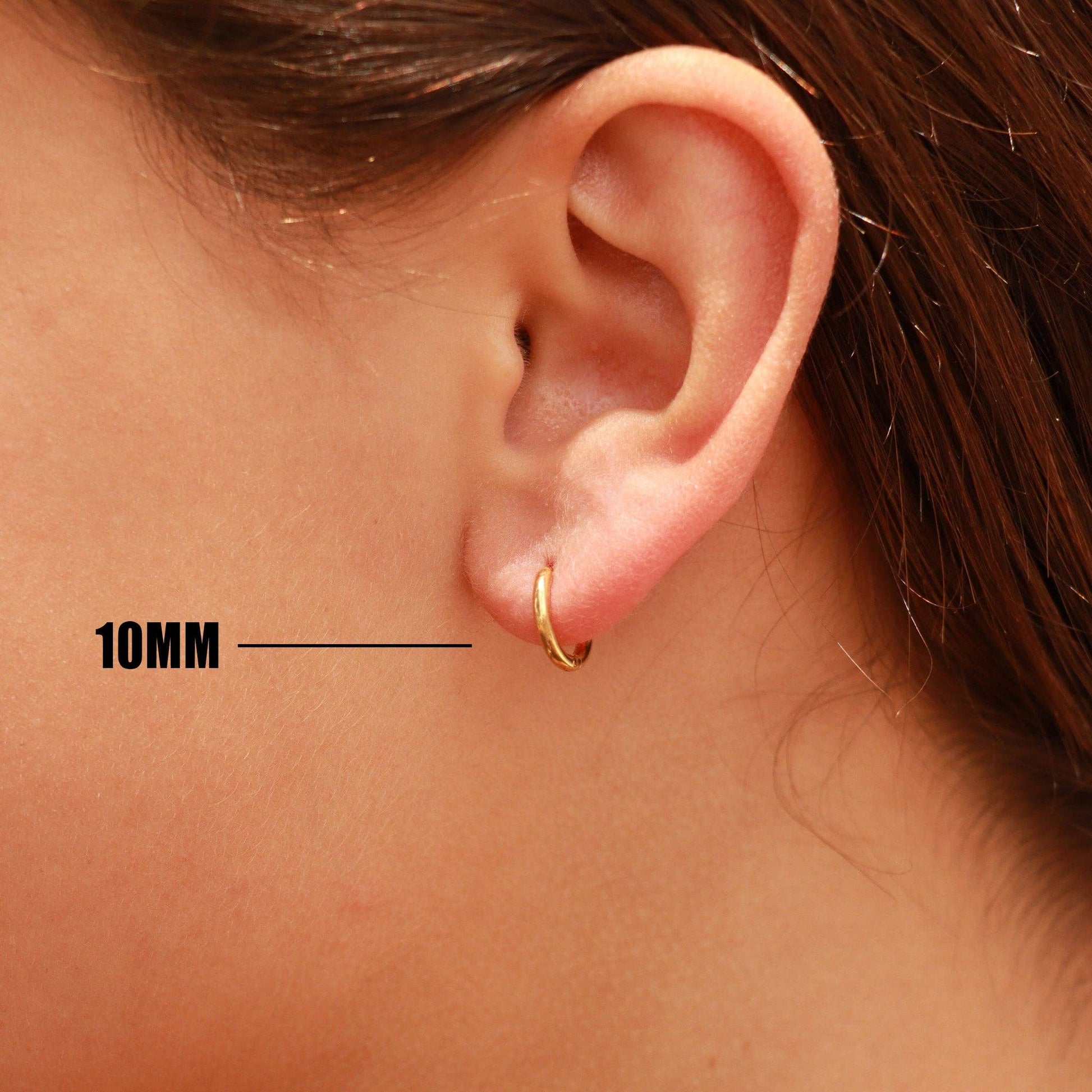 Close-up of an ear wearing a gold hoop earring with a measurement label indicating 10MM.