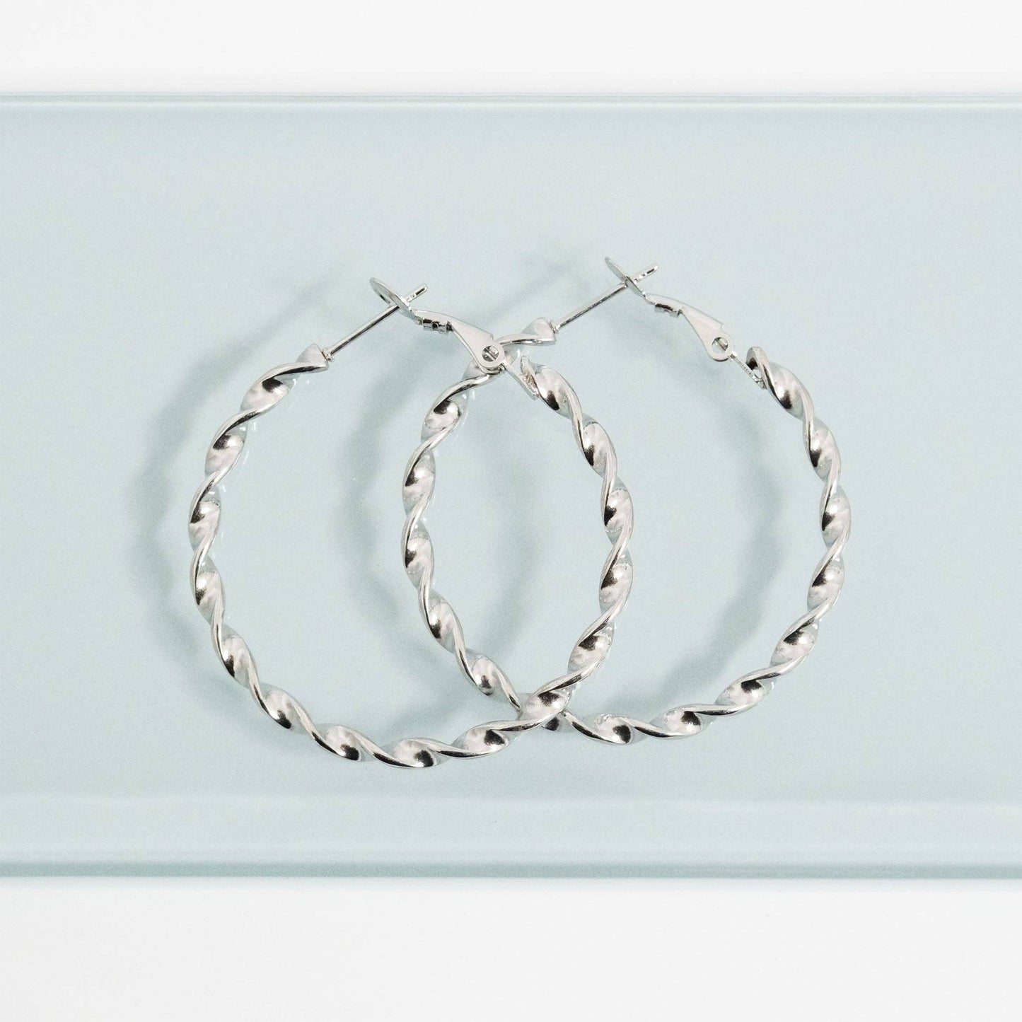 Silver hoop earrings on a light blue background