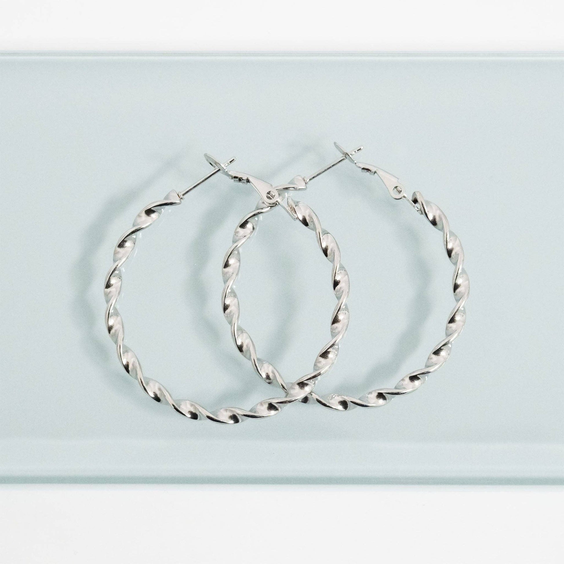 Silver hoop earrings on a light blue background