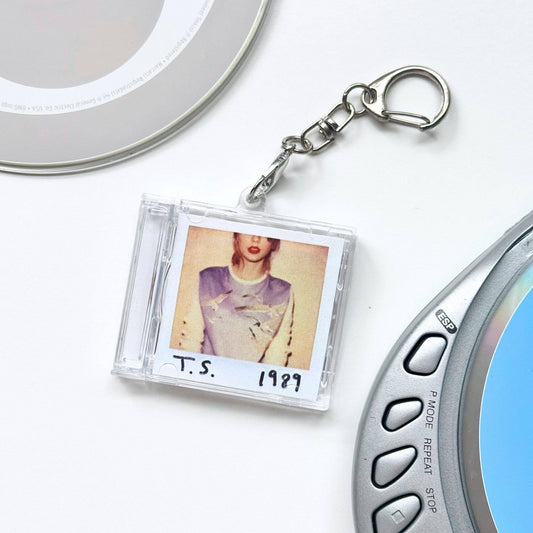 Keychain in the shape of a compact disc with a photo and text on a white background. Taylor Swift 1989